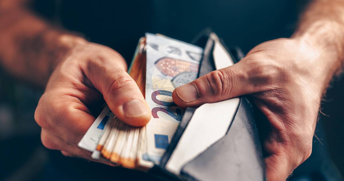 Man met een portemonnee in zijn hand gevuld met geld 
