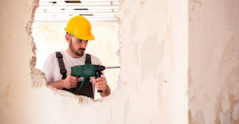 klusjesman, verbouwing, gaten in de muur, klussen, man, verzekeringen, schade zakelijk, gele beschermingshelm